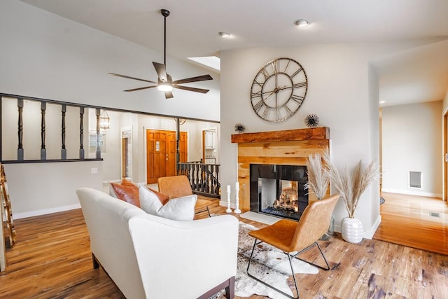 living room featuring a tiled fireplace, vaulted ceiling, light wood-type flooring, and baseboards