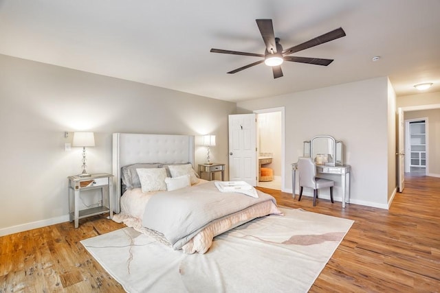 bedroom with ensuite bath, light wood-style flooring, baseboards, and a ceiling fan