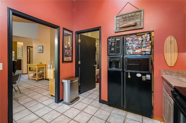 kitchen with light tile patterned floors, stove, and black refrigerator with ice dispenser