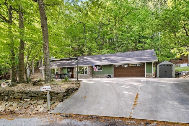 view of front of home featuring driveway, a storage shed, stone siding, an attached garage, and an outdoor structure