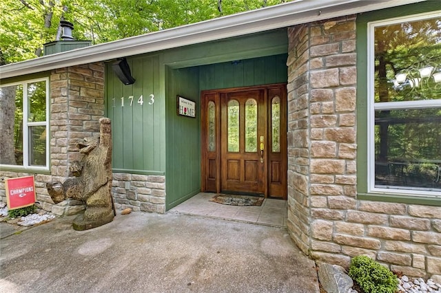 view of exterior entry featuring stone siding and a chimney