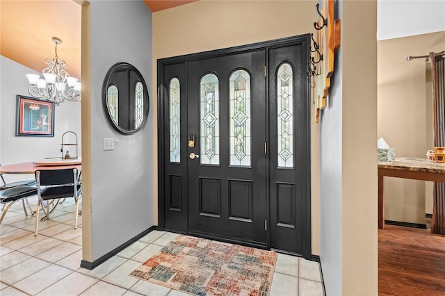 entrance foyer featuring light tile patterned flooring, baseboards, and an inviting chandelier