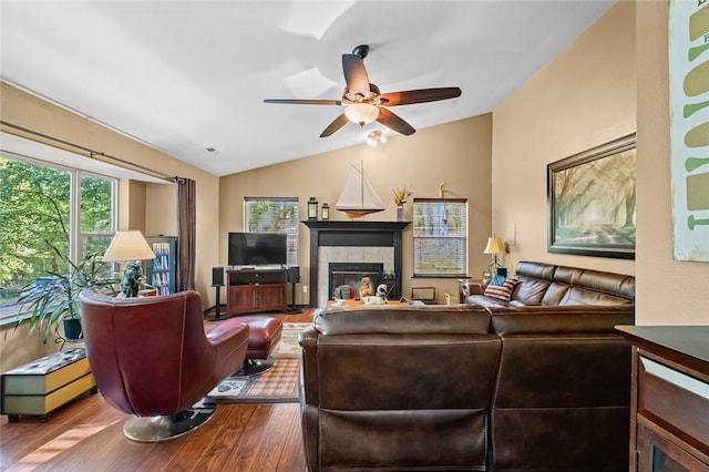 living area with lofted ceiling, dark wood-style floors, a ceiling fan, and a tile fireplace