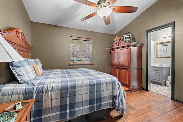 bedroom with ensuite bathroom, lofted ceiling, visible vents, a ceiling fan, and light wood finished floors