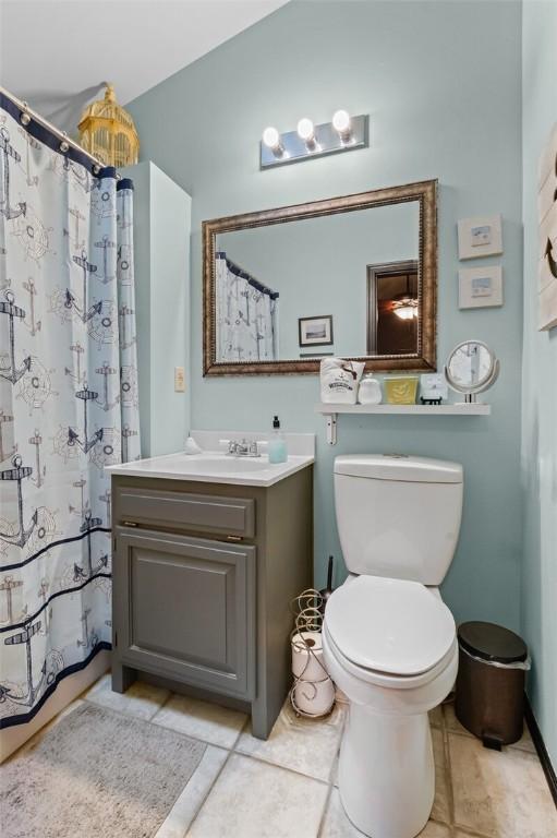 bathroom featuring curtained shower, vanity, toilet, and tile patterned floors