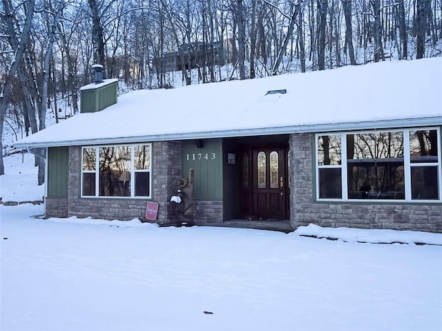 view of front of property featuring stone siding, board and batten siding, and a chimney