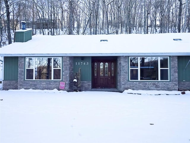 ranch-style home featuring stone siding, a chimney, and board and batten siding