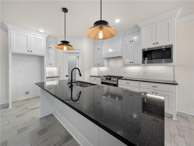 kitchen featuring appliances with stainless steel finishes, white cabinetry, and dark stone countertops