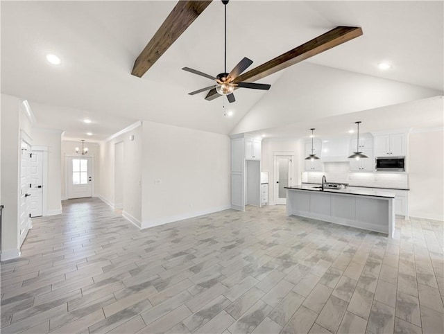 unfurnished living room featuring ceiling fan with notable chandelier, beamed ceiling, light wood-type flooring, and sink