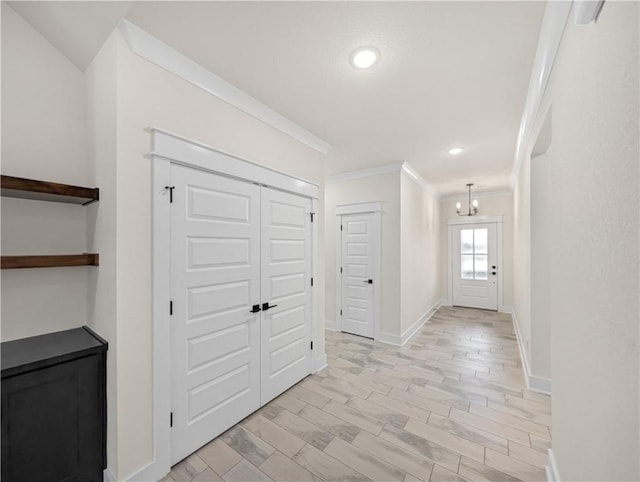 foyer featuring light wood-type flooring, an inviting chandelier, and crown molding