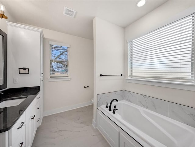 bathroom featuring a washtub, vanity, and toilet