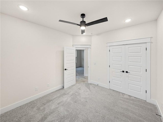 unfurnished bedroom featuring a closet, light colored carpet, and ceiling fan