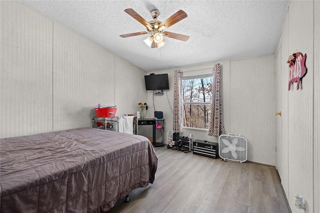 bedroom with a textured ceiling, light hardwood / wood-style floors, and ceiling fan