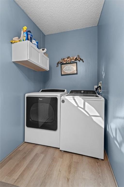 laundry area featuring washer and dryer, light wood-type flooring, and a textured ceiling