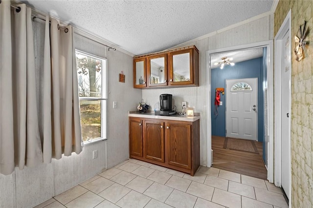 bar with ceiling fan, light tile patterned floors, a textured ceiling, and ornamental molding