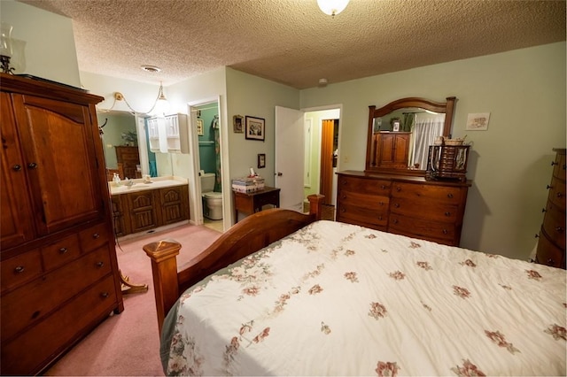 bedroom featuring light carpet, a textured ceiling, and ensuite bath