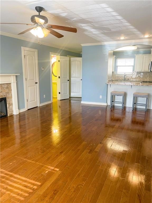 unfurnished living room featuring ceiling fan, hardwood / wood-style floors, and ornamental molding