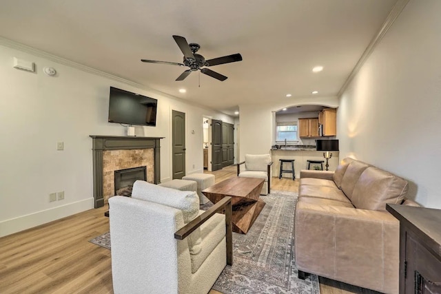 living room with ceiling fan, ornamental molding, sink, and light hardwood / wood-style flooring