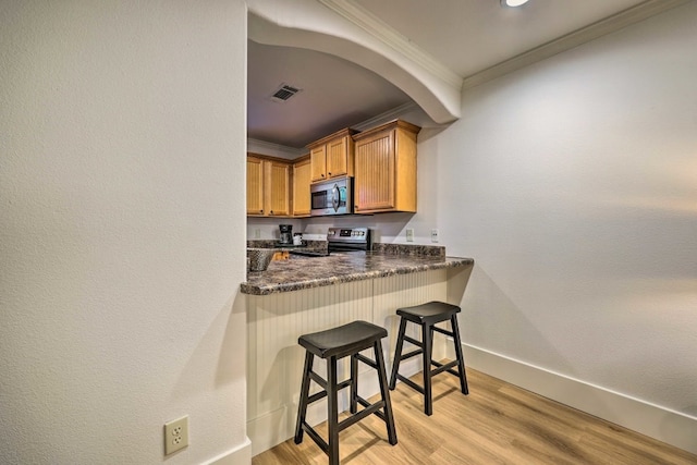 kitchen featuring a kitchen breakfast bar, light hardwood / wood-style flooring, kitchen peninsula, crown molding, and appliances with stainless steel finishes