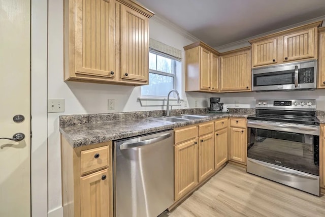 kitchen with sink, stainless steel appliances, light wood-type flooring, and ornamental molding