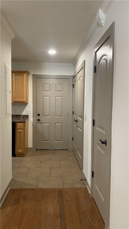 hallway with light hardwood / wood-style floors, crown molding, and electric panel