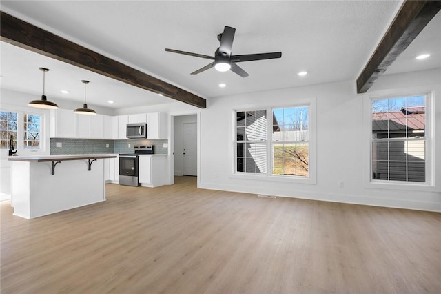 unfurnished living room featuring ceiling fan, beam ceiling, and light wood-type flooring