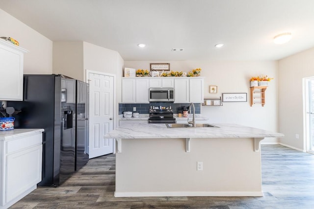 kitchen with appliances with stainless steel finishes, an island with sink, white cabinetry, and sink