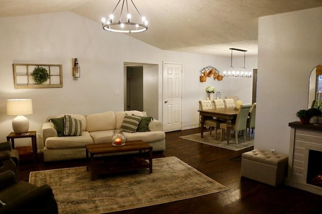 living room featuring a chandelier, dark hardwood / wood-style floors, lofted ceiling, and a brick fireplace