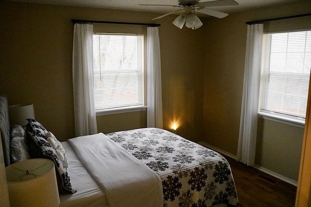 bedroom featuring ceiling fan, dark hardwood / wood-style floors, and multiple windows