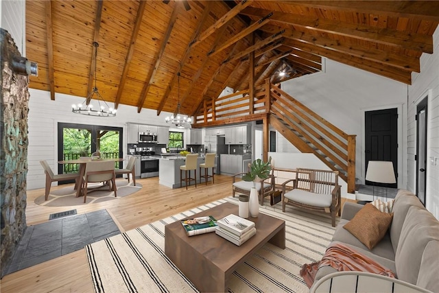 living room featuring beam ceiling, light wood-type flooring, high vaulted ceiling, a chandelier, and wooden ceiling