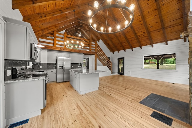 kitchen with backsplash, a kitchen island, beamed ceiling, stainless steel appliances, and high vaulted ceiling