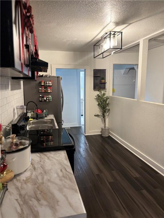 kitchen featuring stainless steel refrigerator, dark hardwood / wood-style floors, sink, and a textured ceiling