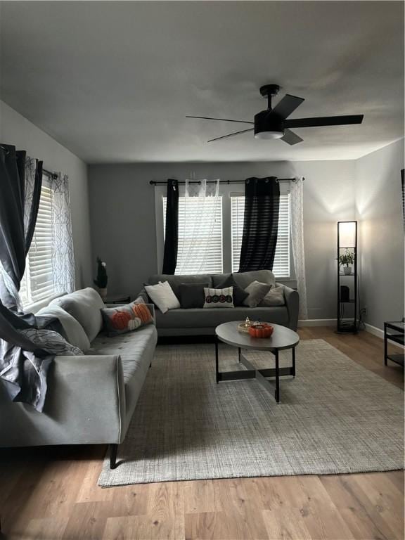 living room featuring ceiling fan, wood-type flooring, and a healthy amount of sunlight