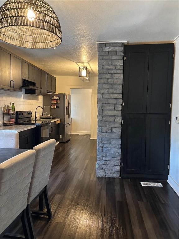 kitchen featuring dark wood-type flooring, backsplash, stainless steel refrigerator with ice dispenser, a textured ceiling, and black / electric stove