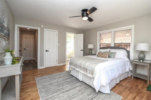 bedroom with ensuite bath, ceiling fan, light hardwood / wood-style floors, and multiple windows