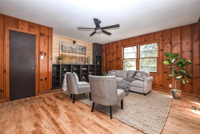 living room with hardwood / wood-style floors, ceiling fan, and wooden walls