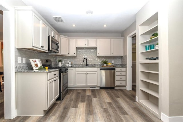 kitchen with white cabinets, dark hardwood / wood-style flooring, stainless steel appliances, and light stone countertops