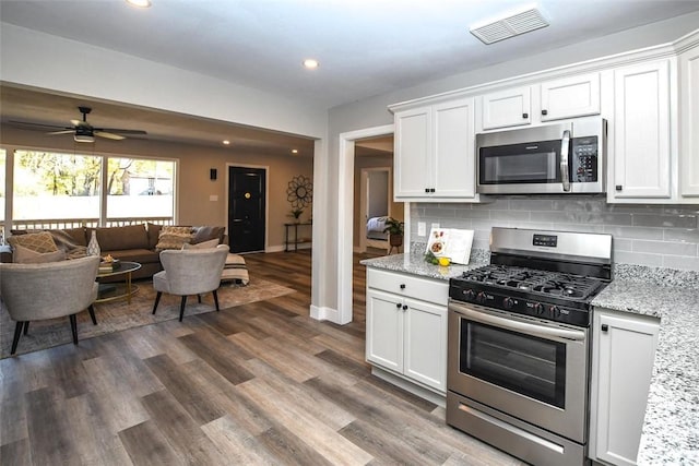 kitchen featuring light stone countertops, tasteful backsplash, stainless steel appliances, ceiling fan, and white cabinetry