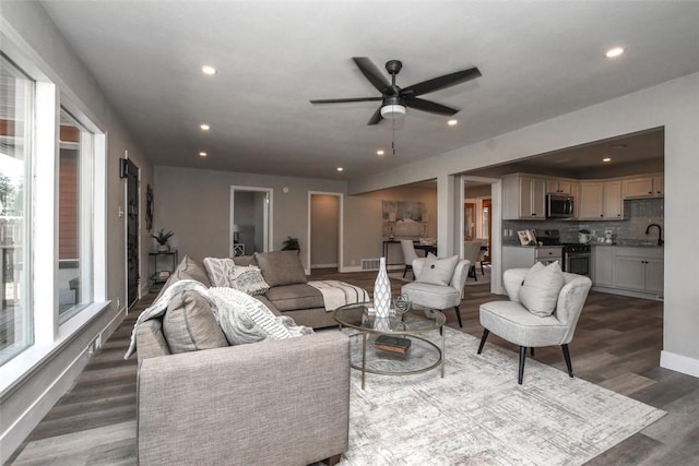 living room with ceiling fan and dark wood-type flooring