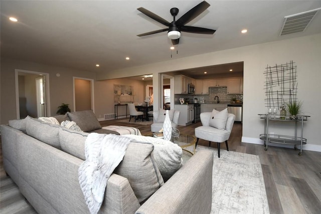 living room featuring dark hardwood / wood-style floors, ceiling fan, and sink