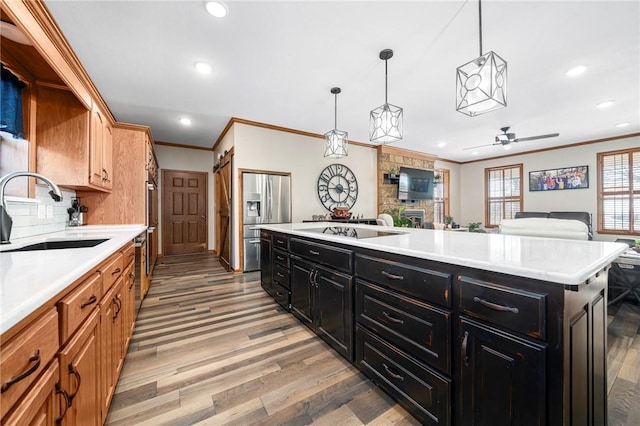 kitchen with light hardwood / wood-style floors, stainless steel appliances, hanging light fixtures, a kitchen island, and sink