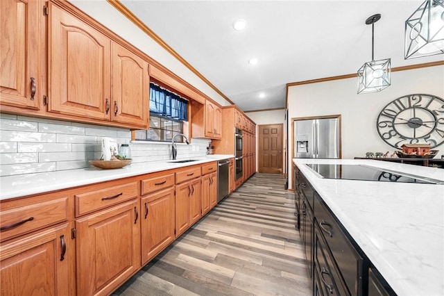 kitchen featuring pendant lighting, stainless steel appliances, tasteful backsplash, sink, and crown molding