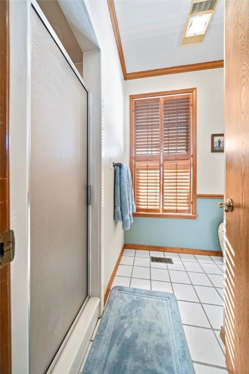 bathroom featuring a shower with shower door, tile patterned floors, and ornamental molding