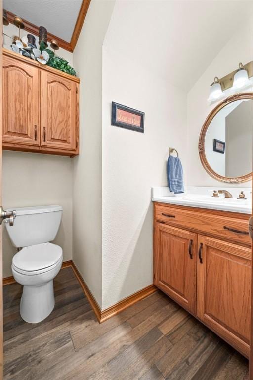 bathroom with toilet, vanity, ornamental molding, and hardwood / wood-style flooring