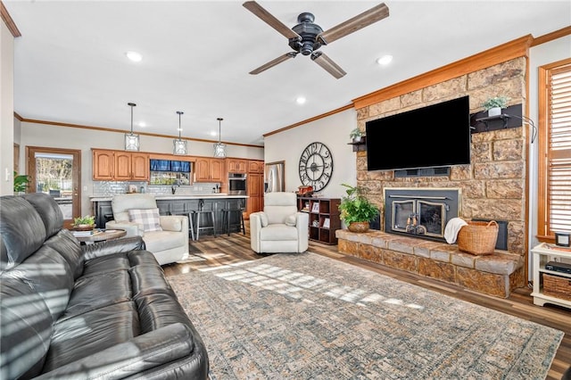 living room featuring ceiling fan, ornamental molding, a fireplace, and hardwood / wood-style floors