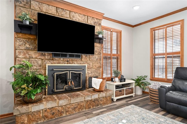 living room with dark hardwood / wood-style floors, crown molding, a stone fireplace, and a healthy amount of sunlight