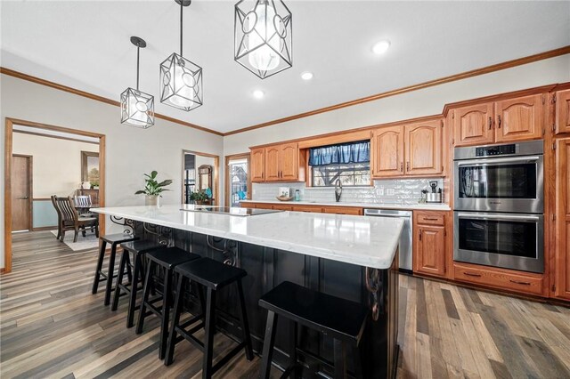 kitchen featuring a spacious island, dark wood-type flooring, stainless steel appliances, tasteful backsplash, and hanging light fixtures