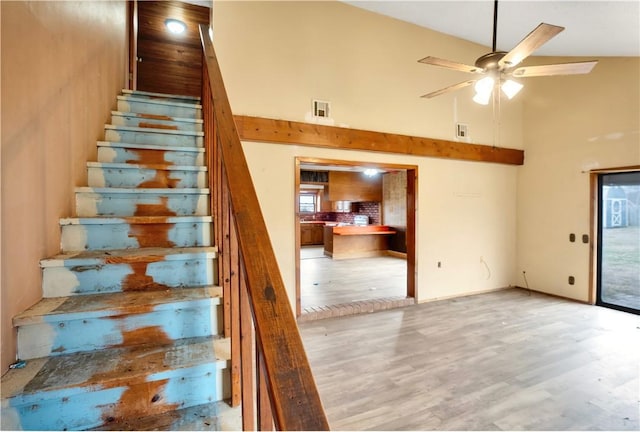 staircase with ceiling fan, high vaulted ceiling, and hardwood / wood-style flooring