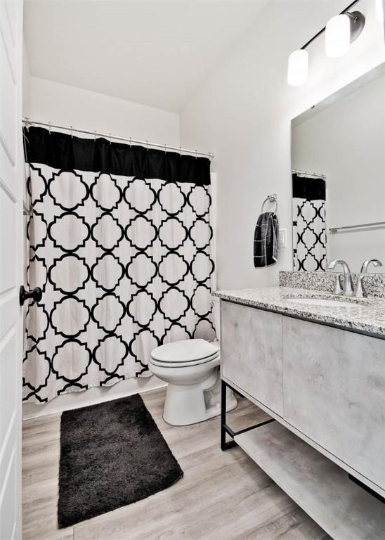 bathroom with hardwood / wood-style flooring, vanity, toilet, and walk in shower