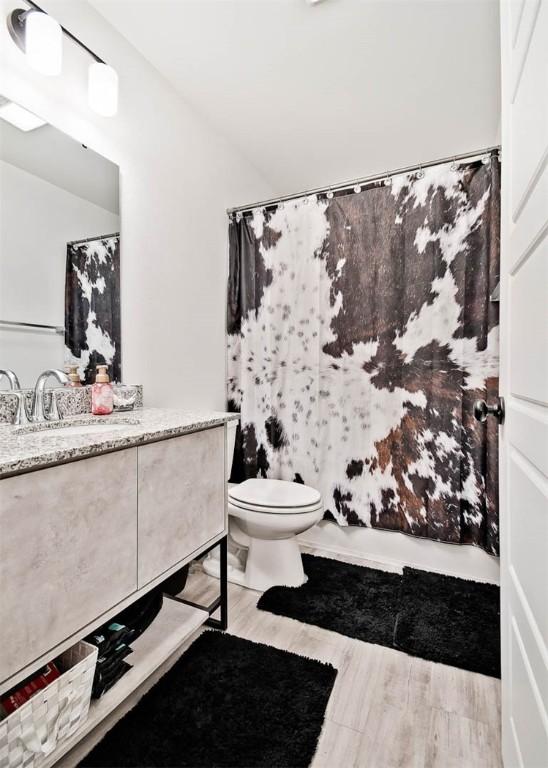 full bathroom with shower / bathtub combination with curtain, vanity, toilet, and wood-type flooring